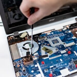 Hand repairing a laptop motherboard with a screwdriver, highlighting tech maintenance.